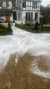 A high-pressure wash cleaning a resin-bound driveway, removing dirt, moss, and stains to restore its original look.